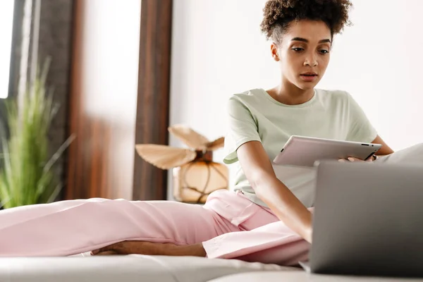 Young Black Woman Using Tablet Computer While Working Laptop Home — Stockfoto