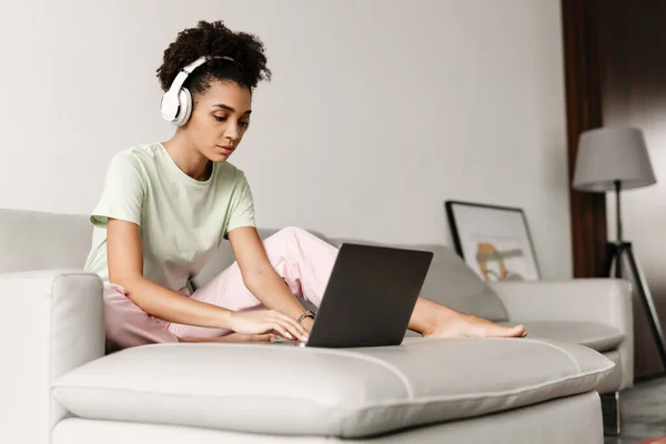 Young Black Woman Headphones Using Laptop While Sitting Couch Home — Stockfoto