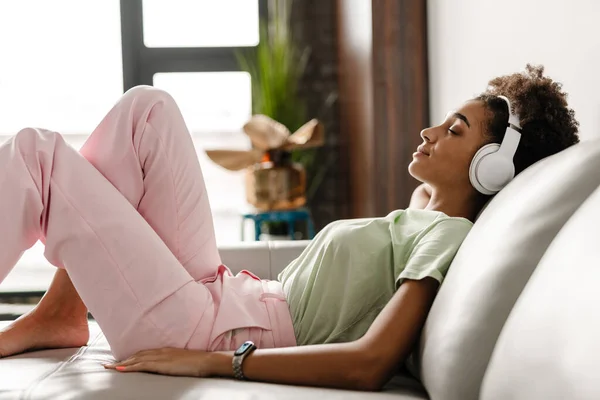 Young Black Woman Listening Music Headphones While Sitting Couch Home — 图库照片
