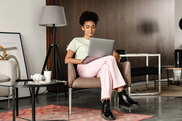 Молода Чорна Жінка Працює Ноутбуком Сидячи Кріслі Вдома — стокове фото