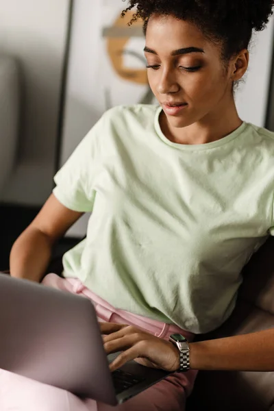 Young Black Woman Working Laptop While Sitting Armchair Home — стоковое фото