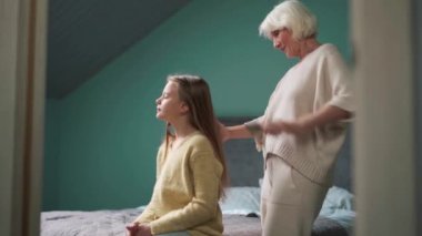 Evde torununun saçını tarayan konsantre bir büyükanne.