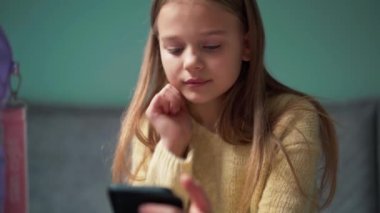 Memnuniyetsiz kız evde telefonla mesajlaşıyor.