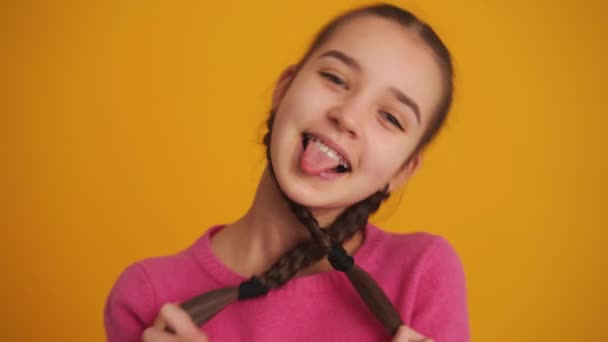 Smiling Girl Pigtails Showing Tongue Camera Yellow Studio — Stockvideo