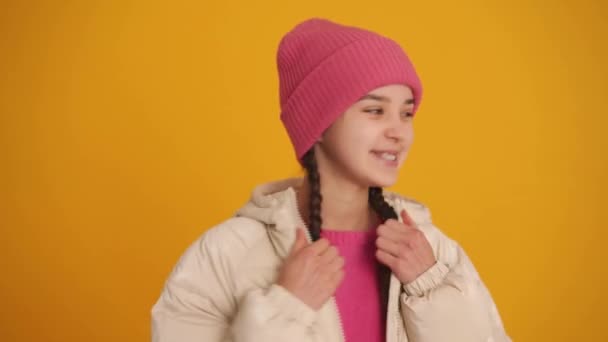 Усміхнена Дівчина Кісками Обманює Камеру Зимовій Куртці Жовтій Студії — стокове відео