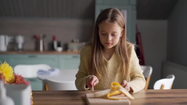 Concentrated Girl Cuts Banana Kitchen — Stockvideo