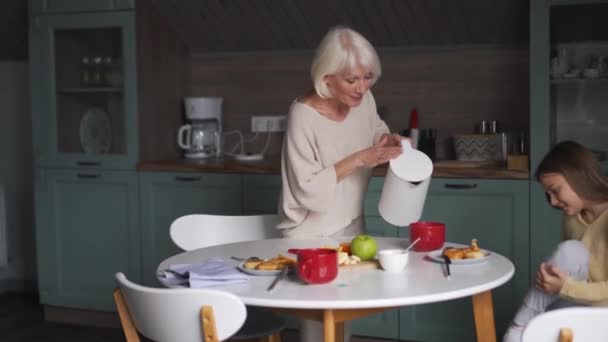 Positive Grandmother Pouring Tea His Granddaughter Kitchen — Wideo stockowe