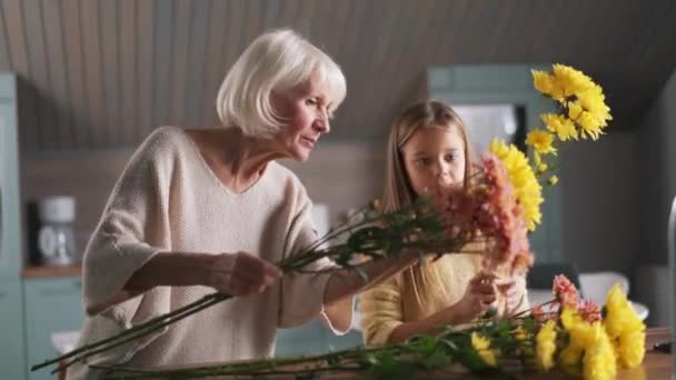 Positive Girl Helps Her Grandmother Collect Bouquet Flowers Home — стоковое видео