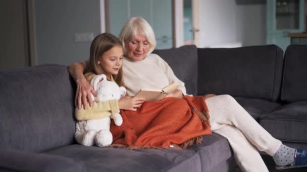 Positive Girl Her Grandmother Reading Book Sofa Home — Vídeo de Stock