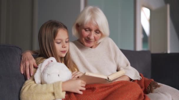 Confident Girl Her Grandmother Reading Book Sofa Home — Stockvideo