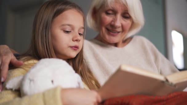 Long Haired Girl Her Grandmother Reading Book Sofa Home — 图库视频影像