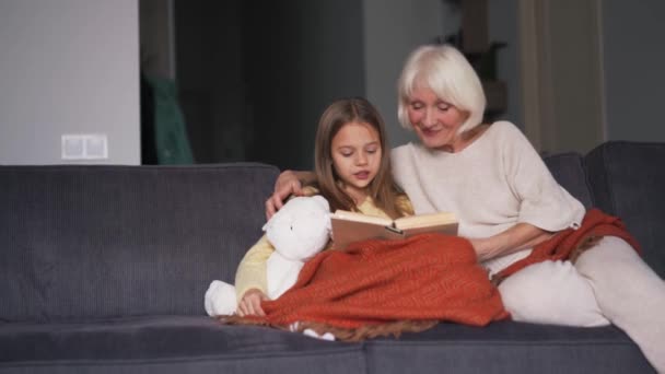 Gadis Berambut Panjang Dengan Neneknya Membaca Buku Sofa — Stok Video
