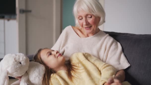 Весела Бабуся Погладжує Онуку Голову Лежачи Дивані — стокове відео