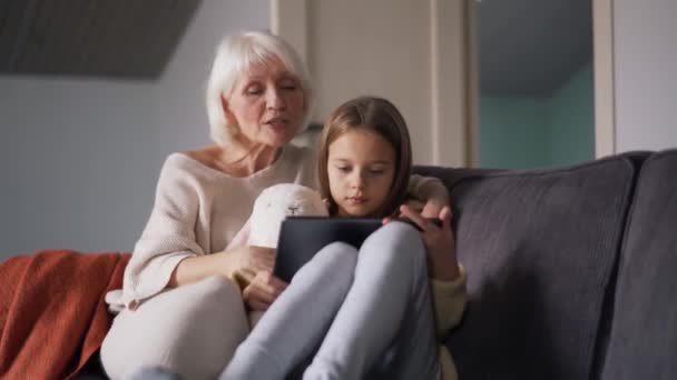 Surprised Grandmother Watching Something Tablet Her Granddaughter Couch — Vídeo de Stock