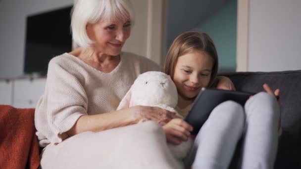 Calm Grandmother Watching Something Tablet Her Granddaughter Couch — Vídeo de Stock