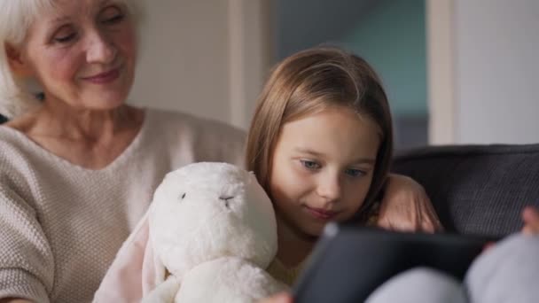 Positive Grandmother Watching Something Tablet Her Granddaughter Couch — Wideo stockowe