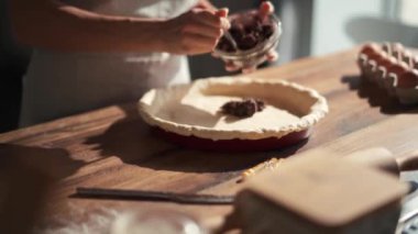 Bir kadın mutfakta hamurun üzerine çikolata koyuyor.