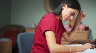 Evdeki not defterine konsantre olmuş ciddi bir kadın.