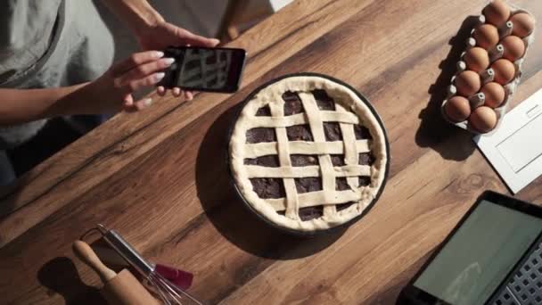 台所で電話でパイの写真を撮る女性 — ストック動画