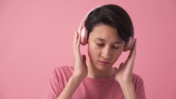 Confident Asian Man Listening Music Headphones Pink Studio – stockvideo