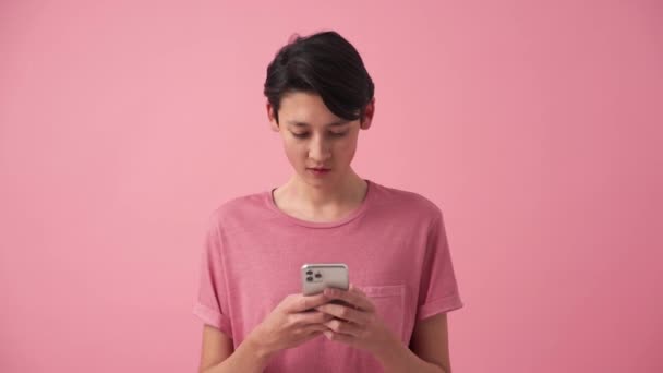 Smiling Asian Man Texting Phone Pink Studio — Vídeo de Stock