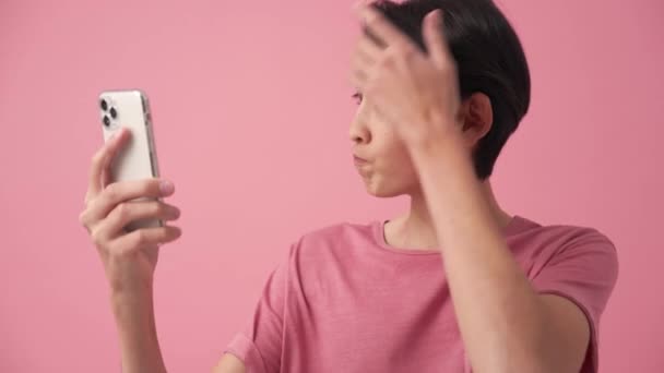 Seriös Asiatisk Man Korrigerar Sin Frisyr Telefon Den Rosa Studion — Stockvideo