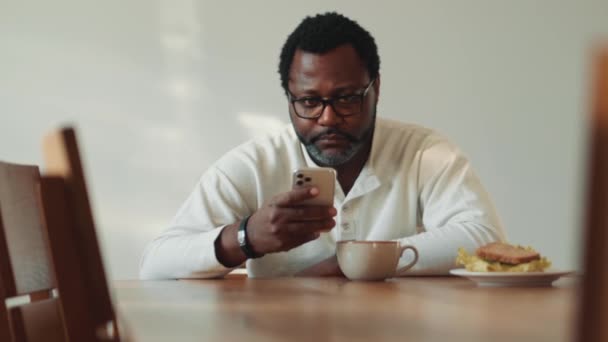 African Confident Man Eyeglasses Looking Phone Having Breakfast Home — Stockvideo