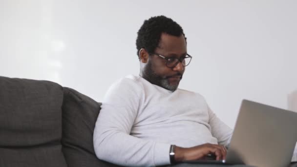 Hombre Africano Serio Que Trabaja Con Papeles Portátil Casa — Vídeos de Stock