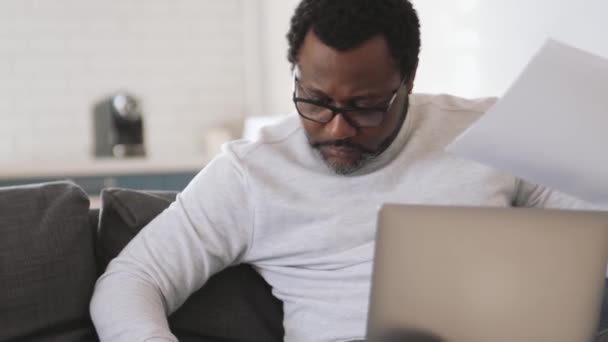 Pensativo Hombre Africano Que Trabaja Con Papeles Portátil Casa — Vídeos de Stock