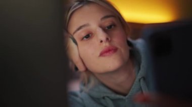 Smiling woman watching something on phone on the bed at home