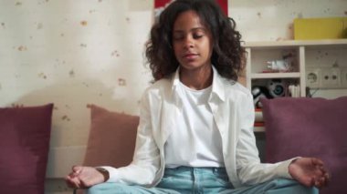 Concentrated African young girl doing meditation at home