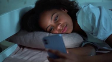 Confident African young girl looking at phone at night