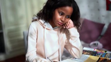 Positive African young girl doing homework at home