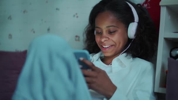 Smiling African Young Girl Headphones Texting Mobile Home — Stok video