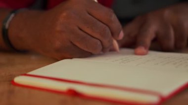 African man writing something in notepad in office at night
