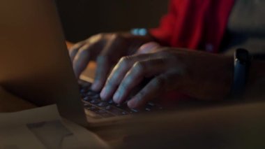 Male hands typing by laptop in office at night