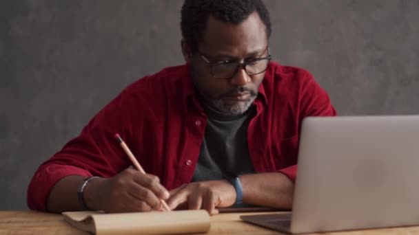 Concentrated African Man Writing Something Laptop Office — Vídeos de Stock