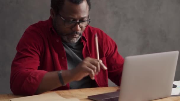 Positive African Man Looking Phone Working Laptop Office — Vídeos de Stock