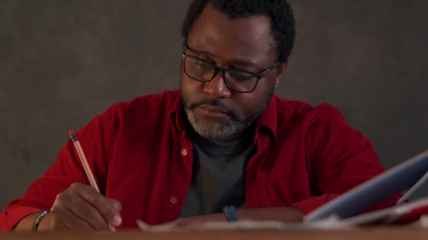 Serious African Man Writing Something Notepad Office Night — Stockvideo
