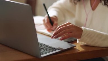 African woman typing and writing in cafe