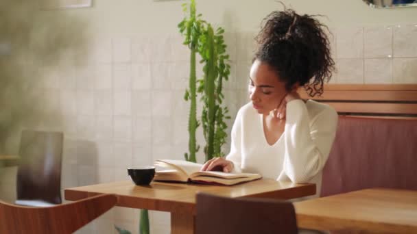 Cheerful African Woman Reading Book Drinking Coffee Cafe — Vídeo de Stock