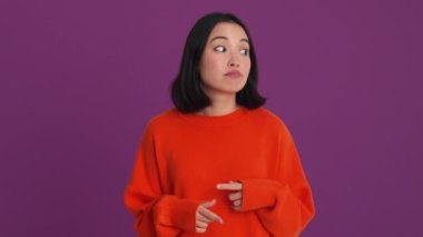 Kırmızı kazaklı sıkıcı kadın mor stüdyoya bakıyor.