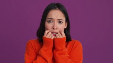 Mor stüdyoda elleri ile gözlerini kapatan korkmuş bir kadın.