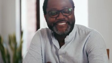 Gözlüklü gülümseyen Afrikalı adam evine bakıyor.