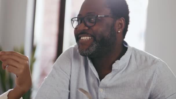 Γελώντας Αφρικανός Γυαλιά Που Τρώει Και Μιλάει Στο Σπίτι — Αρχείο Βίντεο
