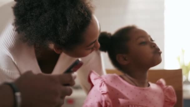 Madre Africana Besando Hija Mejilla Mientras Padre Escribe Teléfono Cocina — Vídeos de Stock