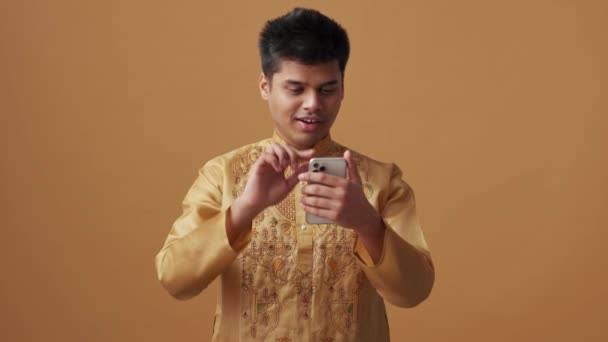 Hombre Indio Feliz Tela Nacional Mirando Teléfono Estudio Naranja — Vídeo de stock