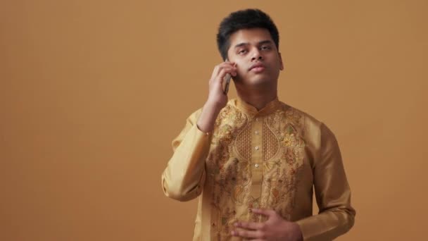 Уверенный Индиец Национальной Одежде Разговаривает Телефону Оранжевой Студии — стоковое видео