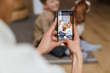 Anne, mutlu oğlunun köpekle oynarken fotoğraflarını çekiyor.