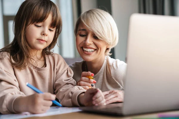 Anne kızına okul ödevlerinde yardım ediyor, dizüstü bilgisayar kullanıyor, karantina sırasında çalışıyor.
